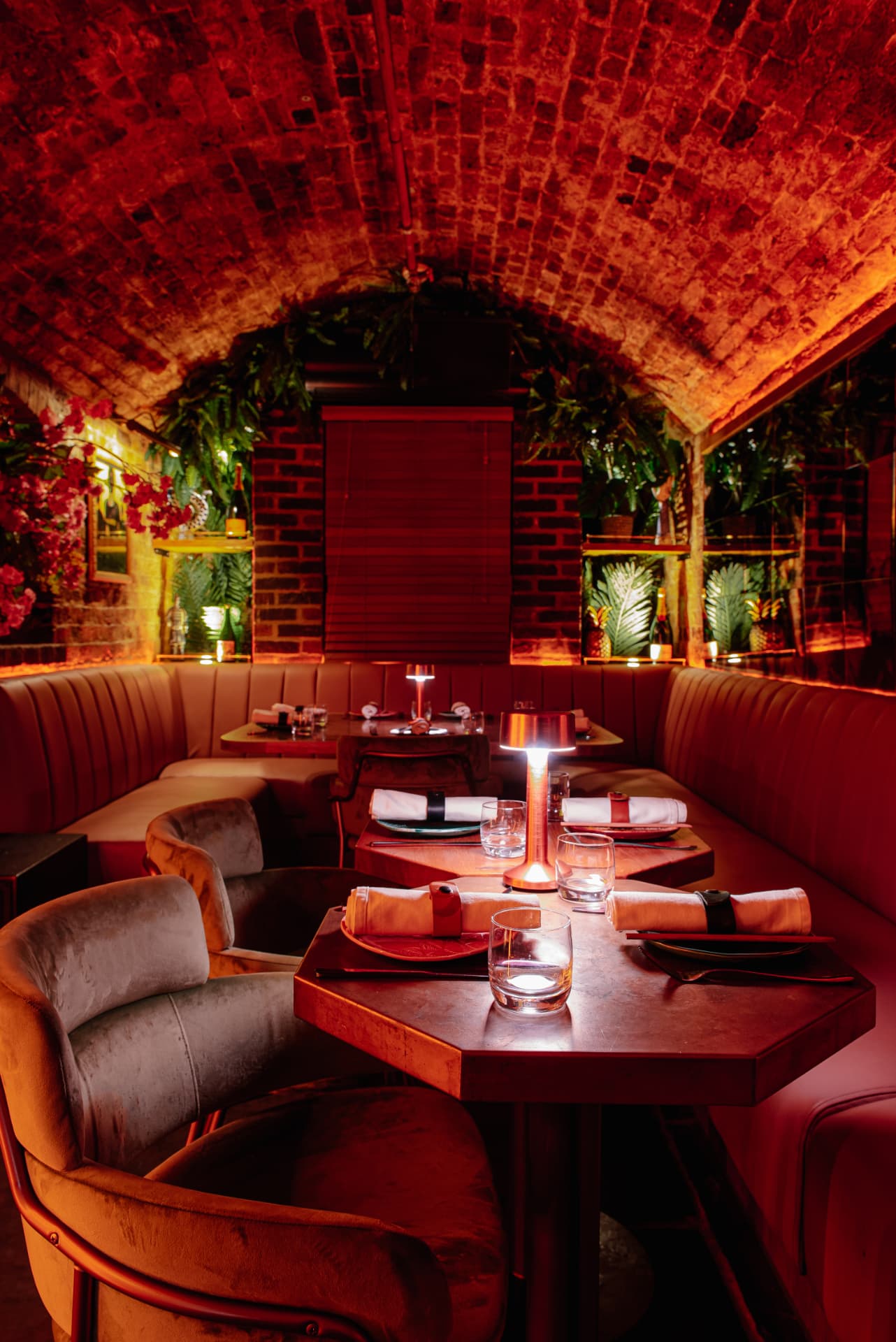 Red-lit banquette seating and hexagonal tables in the Cache Cache vaults