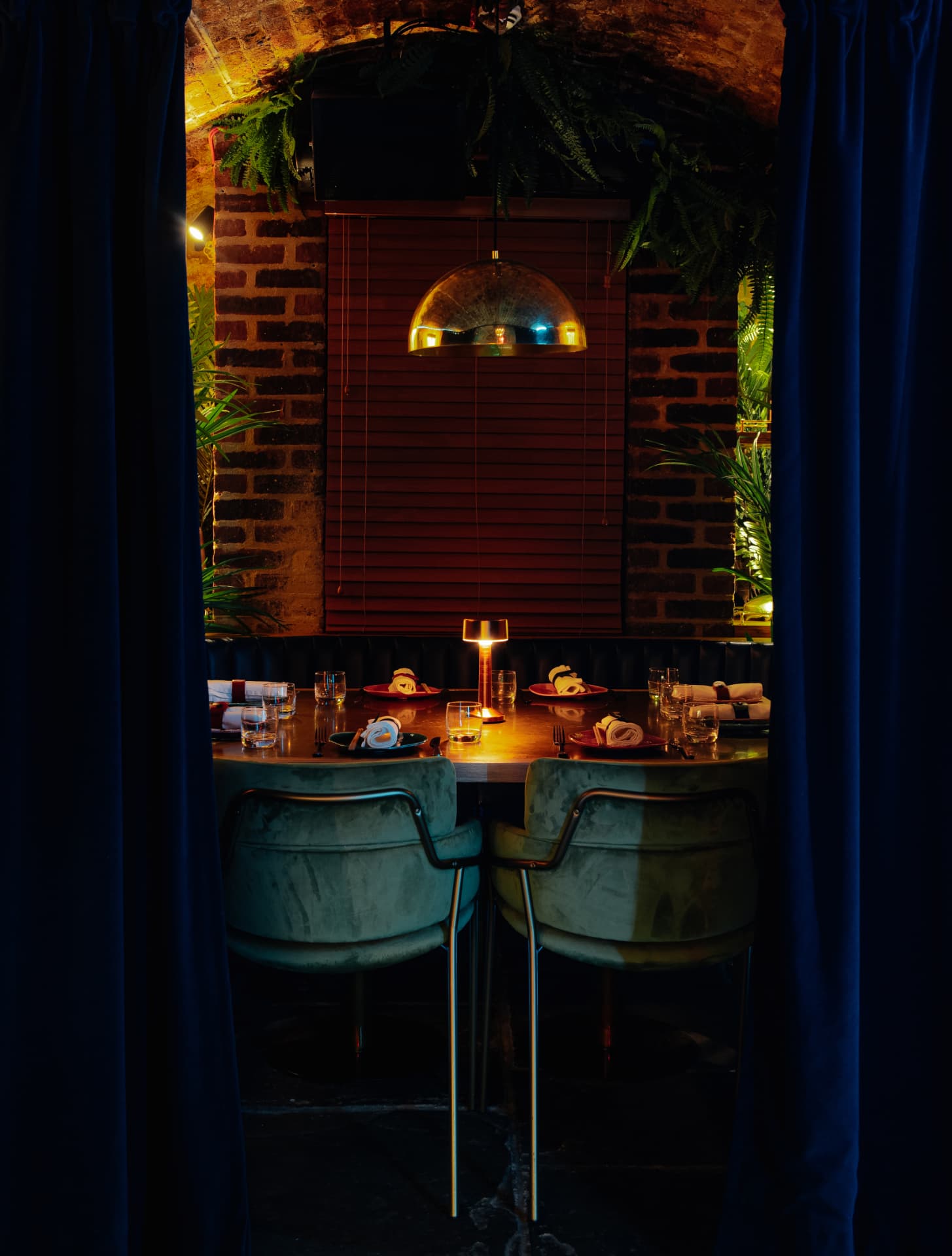A velvet-curtained booth set for dinner beneath the brick vaults